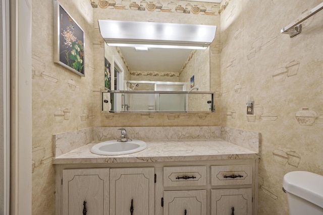 bathroom with toilet, an enclosed shower, and vanity