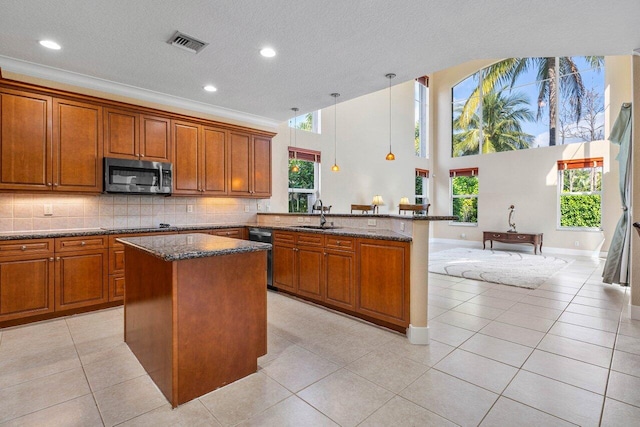 kitchen featuring sink, light tile patterned floors, kitchen peninsula, hanging light fixtures, and a kitchen island