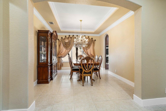 tiled dining space with a raised ceiling, ornamental molding, and a notable chandelier