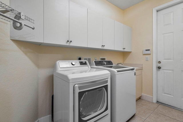 laundry area with independent washer and dryer, cabinets, and light tile patterned floors