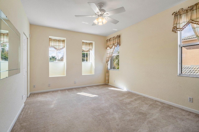 carpeted empty room featuring ceiling fan and plenty of natural light