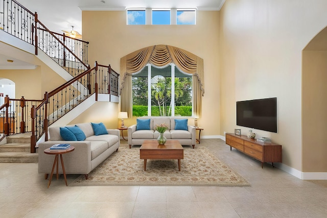 living room with a high ceiling, light tile patterned floors, and crown molding