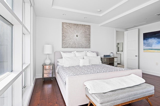 bedroom with dark hardwood / wood-style floors and a tray ceiling