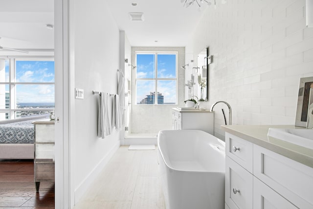 bathroom featuring plus walk in shower, a wealth of natural light, and vanity