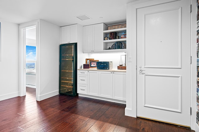 interior space with dark hardwood / wood-style flooring, wine cooler, and white cabinets