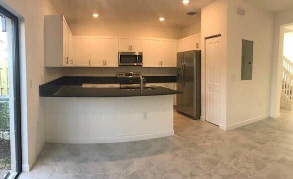 kitchen with electric panel, stainless steel appliances, white cabinetry, and kitchen peninsula