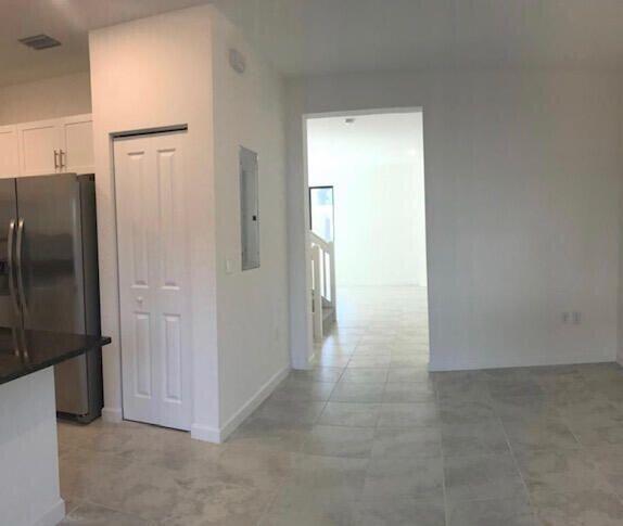 kitchen with electric panel, stainless steel fridge with ice dispenser, and white cabinetry