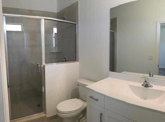 bathroom with toilet, an enclosed shower, and vanity