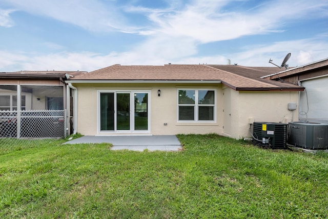 rear view of property with cooling unit, a yard, and a patio