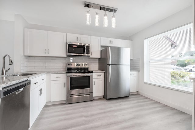 kitchen with stainless steel appliances, white cabinets, pendant lighting, and sink