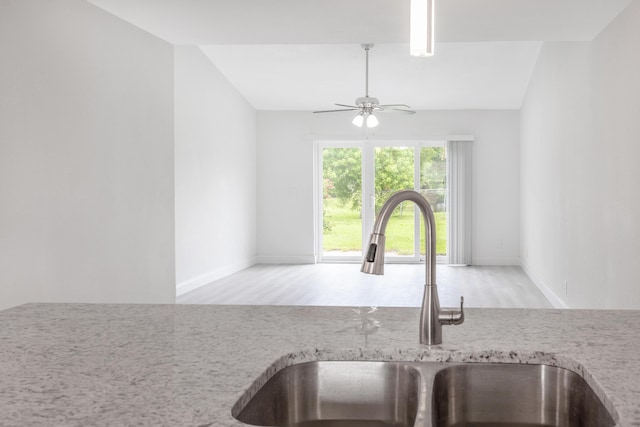 kitchen featuring sink, ceiling fan, light stone counters, and light hardwood / wood-style flooring