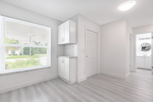 kitchen with white cabinets, light wood-type flooring, and tasteful backsplash