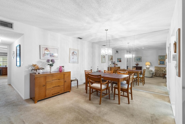 dining area featuring light colored carpet, a textured ceiling, and a chandelier