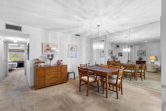 dining space with light carpet, ceiling fan, and a textured ceiling