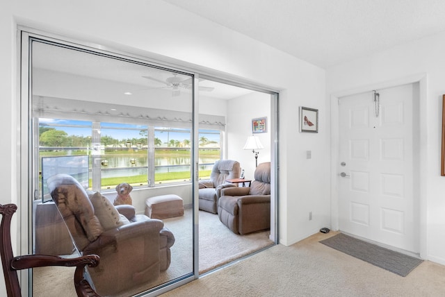 interior space featuring light carpet, ceiling fan, and a water view