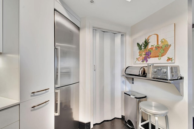 kitchen with dark hardwood / wood-style flooring, built in refrigerator, and white cabinets