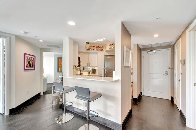 kitchen with stainless steel built in refrigerator, white cabinetry, dark hardwood / wood-style floors, and kitchen peninsula