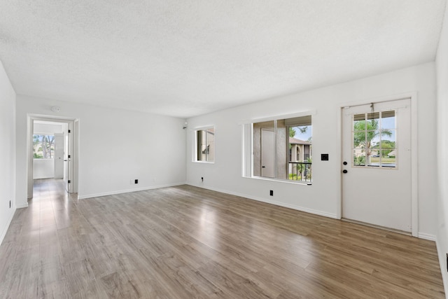 unfurnished living room featuring light hardwood / wood-style floors, a textured ceiling, and plenty of natural light