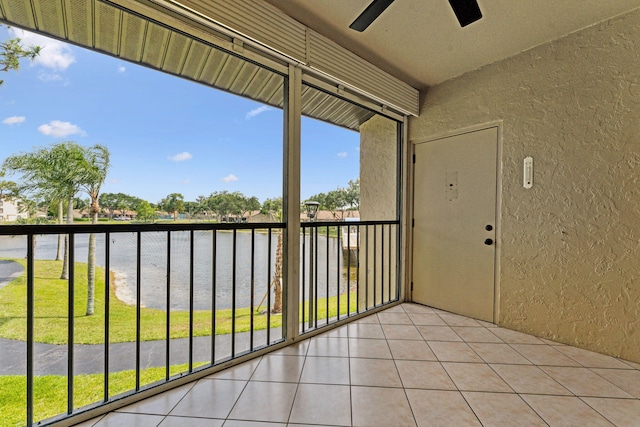 unfurnished sunroom with ceiling fan, a water view, and plenty of natural light