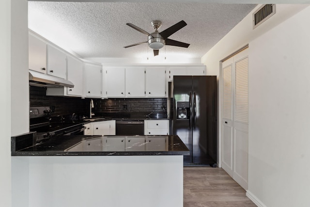 kitchen with kitchen peninsula, a textured ceiling, black appliances, white cabinets, and sink