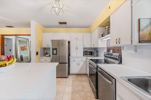 kitchen featuring crown molding, white cabinetry, hanging light fixtures, light tile patterned floors, and stainless steel appliances