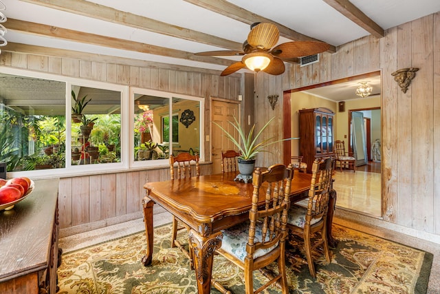 dining area featuring ceiling fan, beam ceiling, and wooden walls