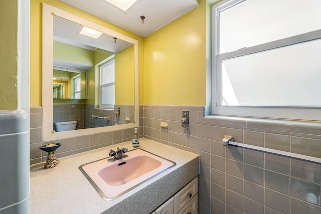 bathroom with tile walls, toilet, and vanity