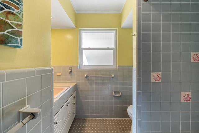 bathroom with vanity, toilet, tile walls, and tile patterned flooring