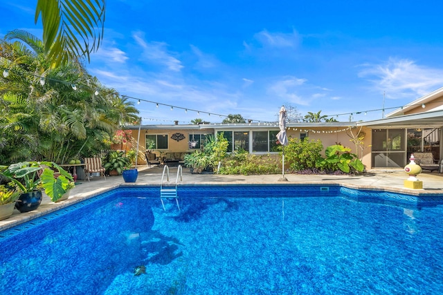 view of swimming pool featuring a sunroom and a patio