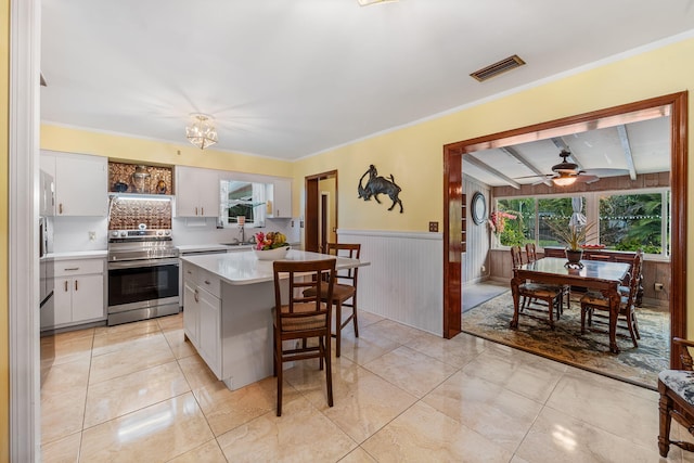 kitchen with ceiling fan, white cabinets, tasteful backsplash, electric range, and a kitchen island