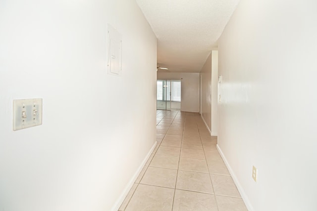 corridor with light tile patterned flooring and a textured ceiling