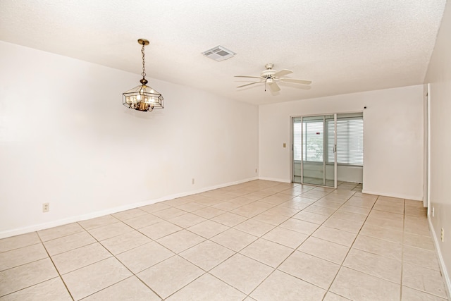 tiled spare room featuring ceiling fan with notable chandelier and a textured ceiling