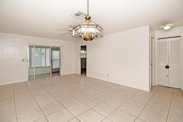 unfurnished room with light tile patterned floors, ceiling fan with notable chandelier, and a textured ceiling