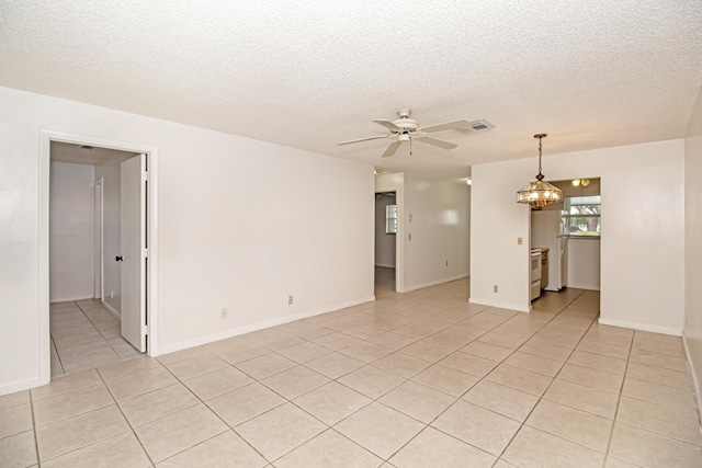 tiled spare room with a textured ceiling and ceiling fan with notable chandelier