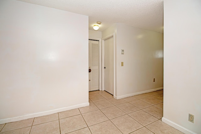 spare room featuring a textured ceiling and light tile patterned floors