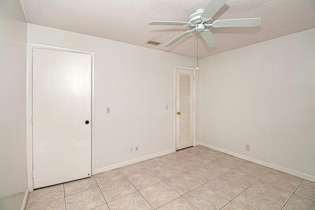 unfurnished bedroom with ceiling fan, light tile patterned floors, and a textured ceiling