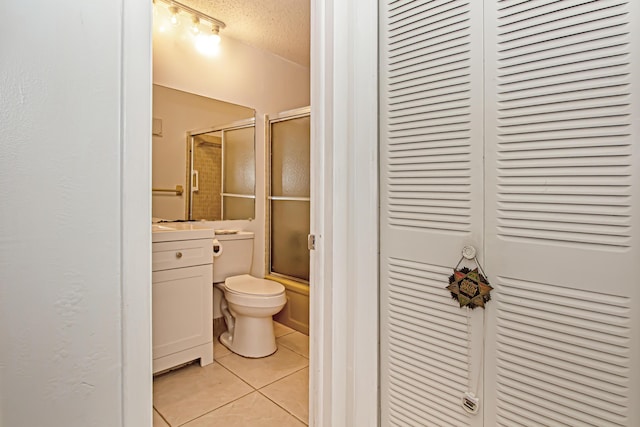 full bathroom featuring toilet, enclosed tub / shower combo, tile patterned flooring, a textured ceiling, and vanity