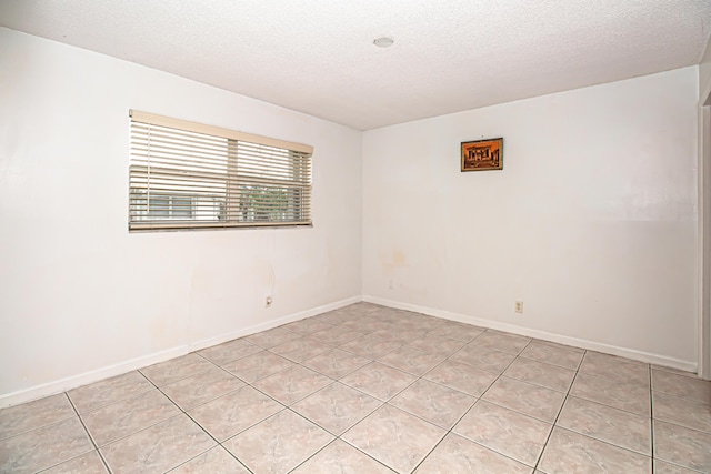 tiled empty room featuring a textured ceiling