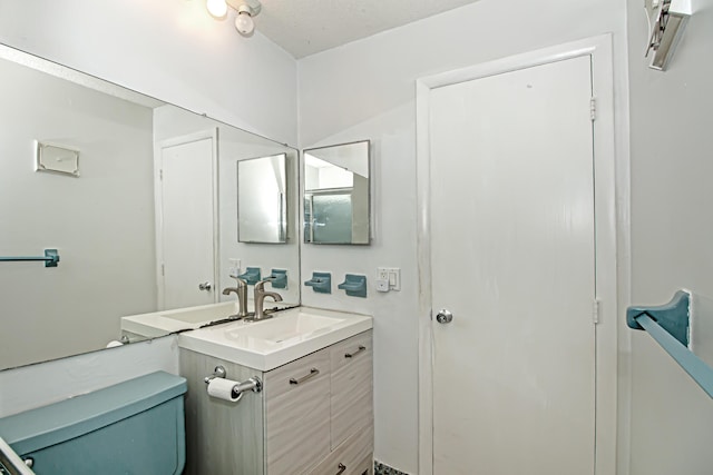 bathroom with a textured ceiling, toilet, and vanity