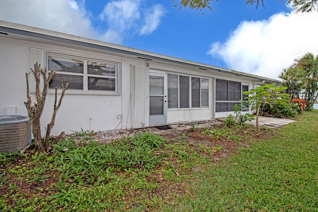 rear view of house featuring central AC and a yard