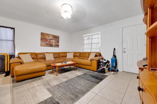 living room with a textured ceiling, ceiling fan, and light tile patterned floors