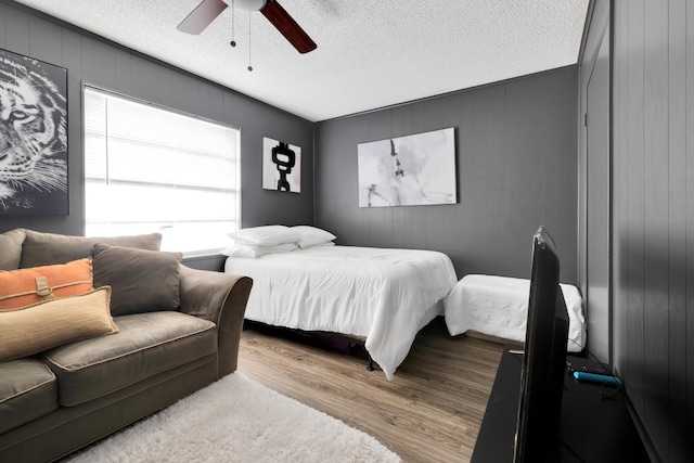 bedroom featuring a textured ceiling, ceiling fan, light hardwood / wood-style flooring, and multiple windows