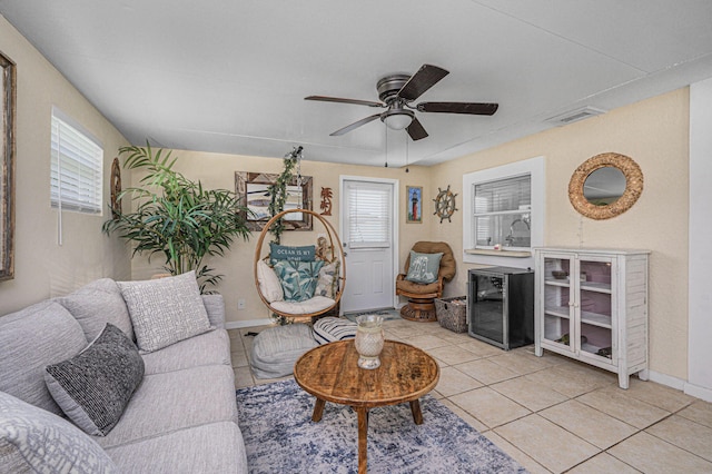 living room with ceiling fan, beverage cooler, a wealth of natural light, and light tile patterned floors