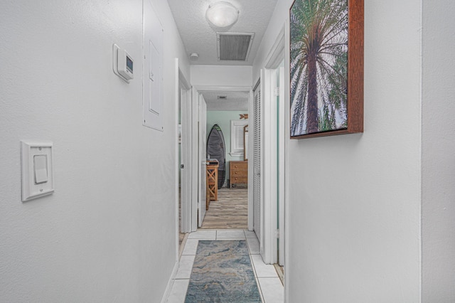 hallway featuring a textured ceiling and light tile patterned floors