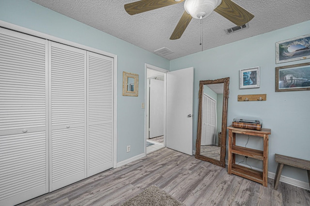 bedroom featuring ceiling fan, light hardwood / wood-style floors, a closet, and a textured ceiling