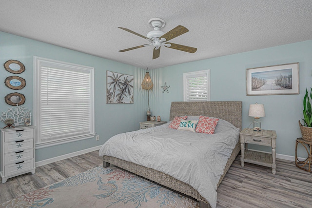 bedroom with a textured ceiling, ceiling fan, and light hardwood / wood-style floors