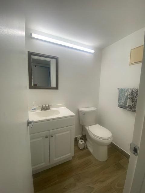 bathroom with toilet, vanity, and hardwood / wood-style flooring