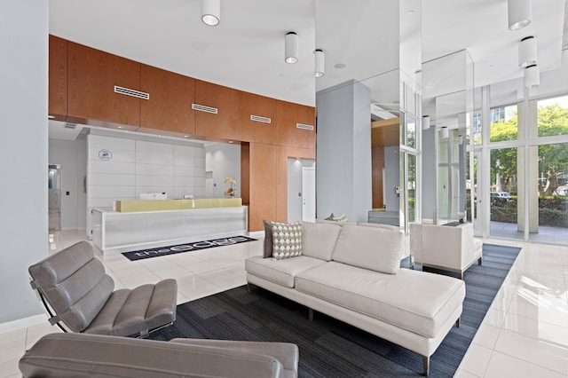 living room featuring wooden walls, light tile patterned flooring, and a high ceiling