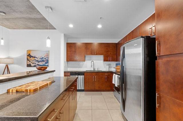 kitchen featuring appliances with stainless steel finishes, sink, dark stone countertops, decorative backsplash, and hanging light fixtures