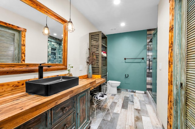 bathroom with vanity, hardwood / wood-style flooring, a shower with shower door, and toilet